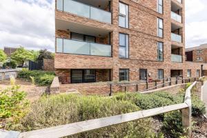 a brick building with a wooden fence in front of it at Stylish & Comfortable Top-Floor Flat in Harrow in London