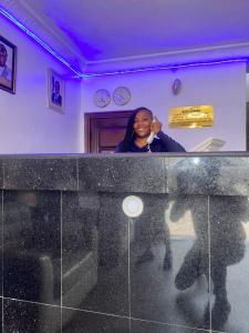 a woman is standing behind a glass counter at Presken Hotel @Villa in Ikeja