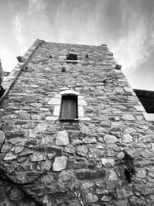 a black and white photo of a stone building with a window at Castle Rizaraki in Kokkala