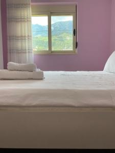 a bedroom with a white bed with a window at Dhimitrulla Guest-House in Përmet