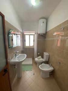 a bathroom with two sinks and a toilet and a window at Dhimitrulla Guest-House in Përmet