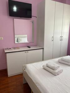 a bedroom with a white bed and a pink wall at Dhimitrulla Guest-House in Përmet +1 photo