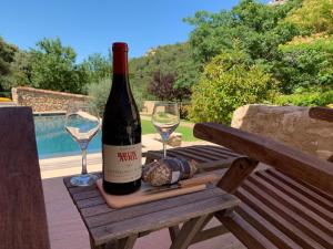 Una botella de vino sentada en una mesa de picnic con dos copas en Clos des Mages en Le Beaucet