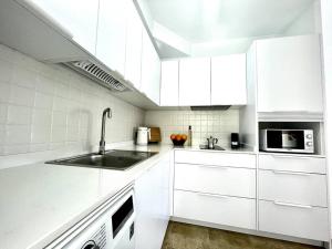 a white kitchen with a sink and a microwave at Iris Apartamento in Arrieta