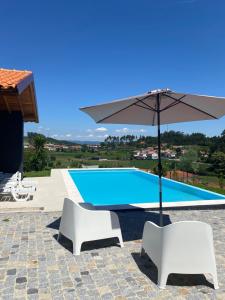 a pool with two white chairs and an umbrella at CASA DAS QUINTÃES in Figueiredo