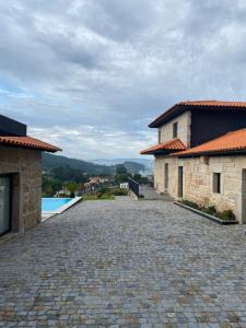 a stone driveway leading to a house and a pool at CASA DAS QUINTÃES in Figueiredo