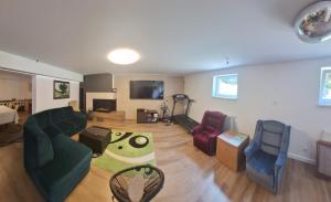 ムロンゴヴォにあるLeśny Dworek - Apartamenty ze wspólnym salonem kominkowym i TVのリビングルーム(緑のソファ、椅子2脚付)