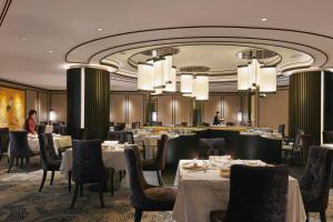 a dining room with tables and chairs and chandeliers at JW Marriott Kuala Lumpur in Kuala Lumpur