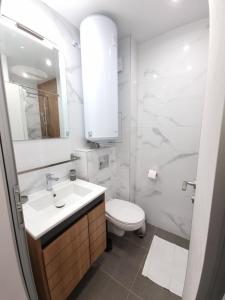a white bathroom with a sink and a toilet at Апартамент Орех А30 in Varna City