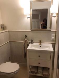 a woman taking a picture of a bathroom with a toilet and sink at Zaciszny dom in Szczecin