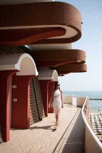 a woman walking down a boardwalk next to the beach at Hotel Flamingo in Gatteo a Mare