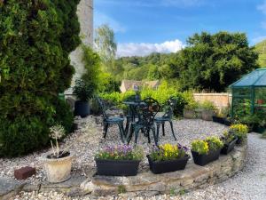 a garden with a table and chairs and flowers at Cupcake Cottage: Quintessential Cotswold Cottage in Nailsworth