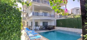 a house with a swimming pool and lounge chairs at Begonville Villas Ladies Beach in Kusadası