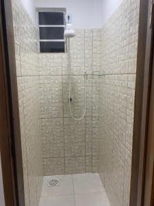 uma casa de banho com um chuveiro e uma porta de vidro em Hostel Flor de Ipê em Barreirinhas
