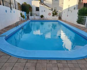 uma grande piscina com água azul num edifício em 1 минута до пляжа, кондиционер, барбекю, wi-fi em Playa de las Americas