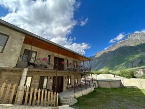 a building with a fence in front of a mountain at Hill House in Kazbegi
