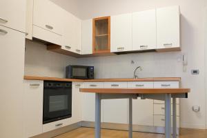 a kitchen with white cabinets and a sink and a microwave at TulipHouse da Davide in Bologna