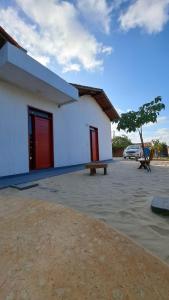 a white building with red doors and a bench at Hostel Flor de Ipê in Barreirinhas
