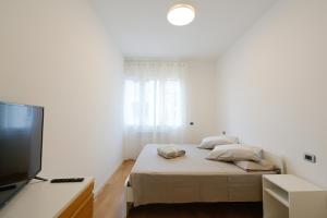 a white bedroom with a bed and a flat screen tv at TulipHouse da Davide in Bologna