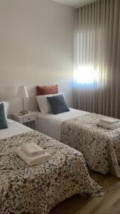 1 dormitorio con 2 camas y mesa con lámpara en CASA DAS QUINTÃES 