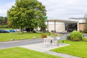 a building with a white bench in front of a road at Holiday Inn Newcastle Gosforth Park by IHG in Newcastle upon Tyne