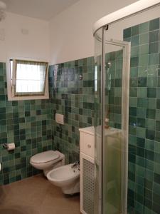 a green tiled bathroom with a toilet and a shower at VELA BLU in Ceriale