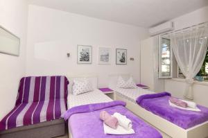 2 Betten mit lila Kissen in einem Zimmer mit Fenster in der Unterkunft Apartments Bernarda in Makarska