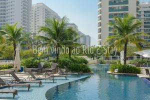 una piscina con sillas y palmeras en una ciudad en 10 Suite Verano Stay Barra, en Río de Janeiro