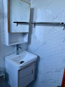 a white bathroom with a sink and a mirror at Madome Aparta Hotel in Pedernales