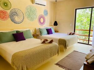 two beds in a room with a window at sunsteps mandalas room in Holbox Island