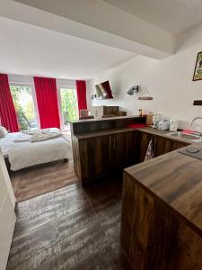 a bedroom with a bed and a kitchen with red curtains at Seaside-Townhouse in Timmendorfer Strand