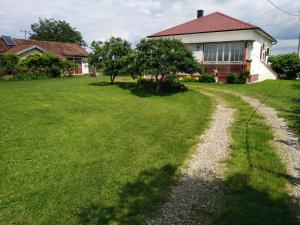 a house with a grass yard with a gravel road at Blossom Cottage in Laktaši