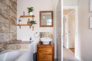 a bathroom with a tub and a sink and a mirror at Quiet 2 bedroom home with cozy fire. in Ebchester