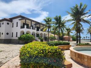 una gran casa blanca con palmeras y una piscina en Beachfront Condo directly on the private beach - Ground Floor en Six Huts
