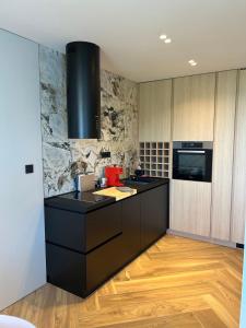 a kitchen with a black counter top and wooden floors at Canova Apartment in Labin