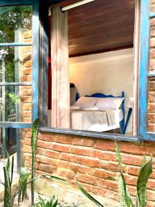 a bed in a window of a brick house at Casa Selva - Vila do Abraão - Ilha grande in Abraão