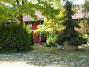 ein rotes Haus mit einem Baum im Hof in der Unterkunft Ferienwohnung Roeder Mühle in Peterfecking