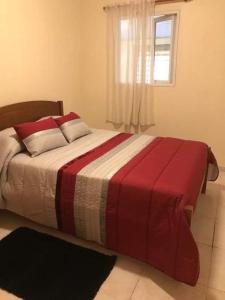 um quarto com uma cama com um cobertor vermelho e branco em caminho da praia da maiata em Porto da Cruz