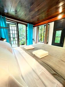 a large bed with two pillows in a room with windows at Casa Selva - Vila do Abraão - Ilha grande in Abraão