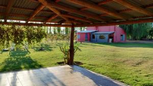 an outside view of a yard with a pink building at Las Potrancas cabaña in General Alvear