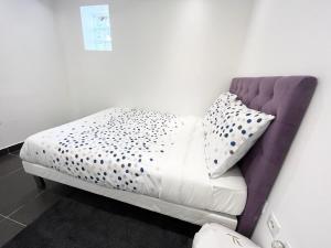 a bed with a purple headboard and pillows on it at Appartement élégant - 12min CDG in Dammartin-en-Goële