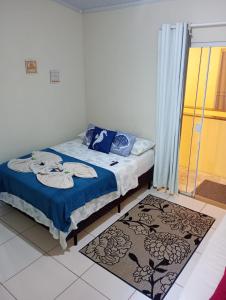 a bedroom with a bed with blue sheets and a window at Flats Jordão in Abraão