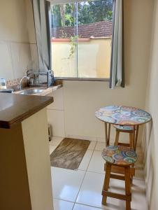a small kitchen with a table and two stools at Flats Jordão in Abraão