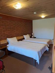- 2 lits dans une chambre avec un mur en briques dans l'établissement Hotel Artesanos, à Villa Alegre