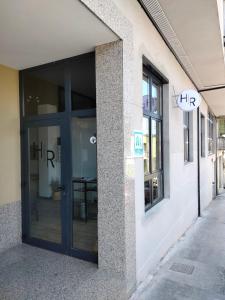 una entrada a un edificio con una gran puerta de cristal en Albergue HR, en Sarria