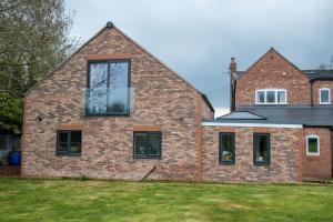 a brick house with large windows on a yard at Meadow Bank, fabulous apartment in Baddiley