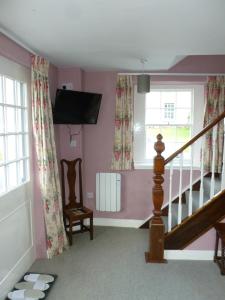 a living room with pink walls and a staircase at The Coach House, Hesket Newmarket in Hesket Newmarket