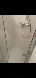 a shower with a hose in a white bathroom at Chambre double privée in Annemasse