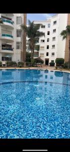 a large swimming pool with blue tiles in front of a building at Lux furnished flat Enjoy ur stay in Nouaceur