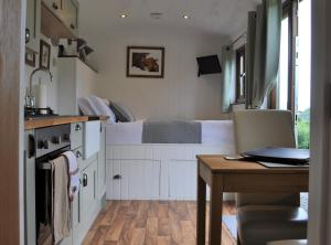 a kitchen with a bed and a table and a kitchen with a desk at Fullabrook Farm Retreat, The Shepherdess Hut in West Down